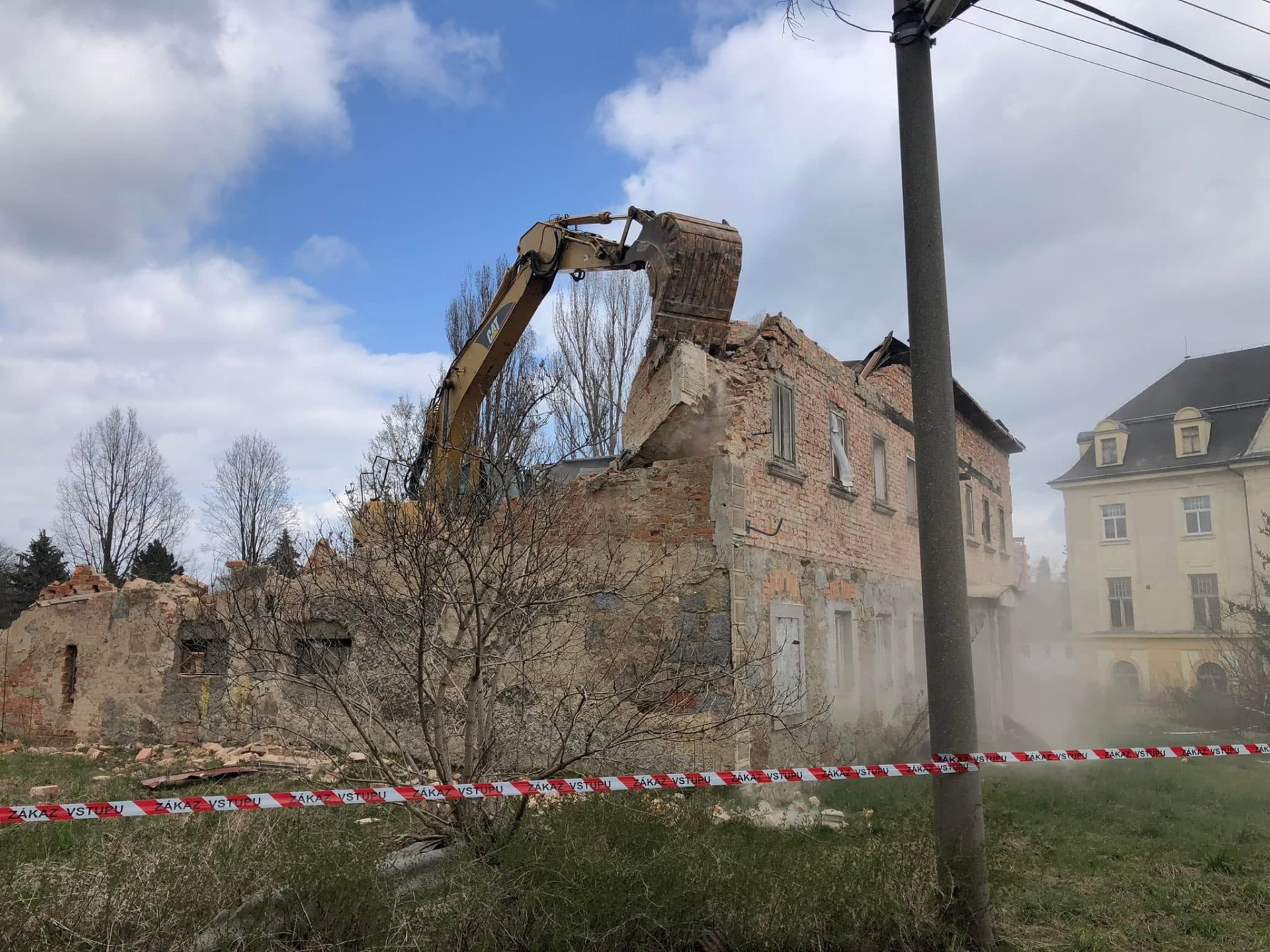 Bagr při demolici zděného objektu